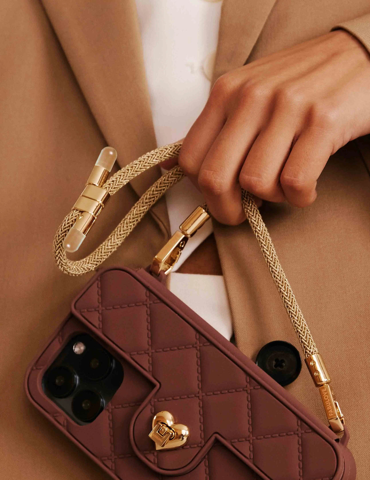Macro shot: Golden Bling Bling wristlet strap with intricate texture and tiny bulb design, casually coiled and attached to chocolate SOL PURSE CASE. STRAPS.
